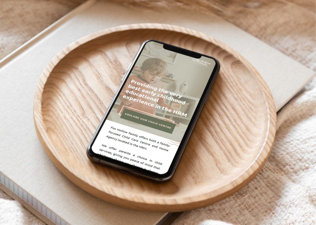 Cell phone on a wood dish with Fox Hollow Family website open on screen